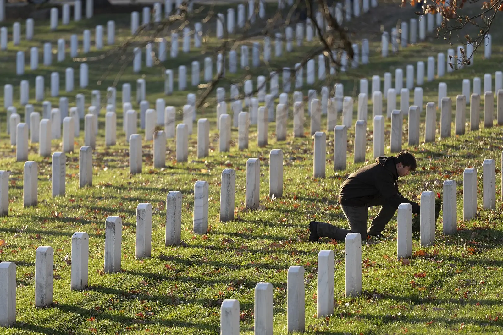 A volunteer lays a holiday wreath at a headstone in Section 37 of Arlington National Cemetery.